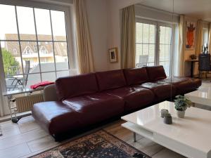 un divano in pelle marrone in un soggiorno con finestre di fewo1846 - Wellenrauschen - strandnahes Apartment mit Balkon und Meerblick a Harrislee
