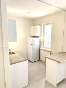 a kitchen with white cabinets and a refrigerator at Yksiö ilmaisella autopaikalla in Jyväskylä +4 photos