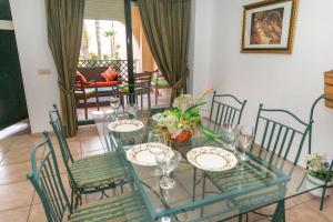 a glass table with chairs and plates on it at Chalet Adosado Susurros Marinos in Zahara de los Atunes