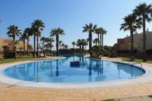 a large pool with palm trees in a park at Chalet Adosado Susurros Marinos in Zahara de los Atunes