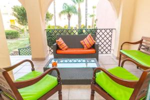a porch with two chairs and a couch and a table at Chalet Adosado Susurros Marinos in Zahara de los Atunes