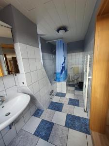 ein Badezimmer mit einem weißen Waschbecken und einer blauen Dusche in der Unterkunft Nordsee-Hafen Apartment-Zentrale Ferienwohnung in Wilhelmshaven