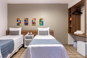 a bedroom with two beds and a painting on the wall at Citi Hotel Express Caruaru in Caruaru