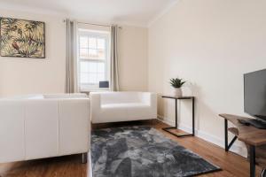 a living room with a white couch and a television at Ely Stays Flat 1 Stylish City Centre Apartment in Ely