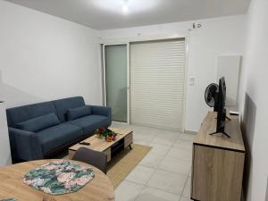 a living room with a blue couch and a tv at Le Gosier Coastal Residence in Le Gosier