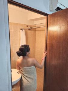 Una mujer parada frente a la puerta de un baño. en Habitacion tipo hotel centrico 3 camas, cocina,WIFI E, en Ciudad Valles