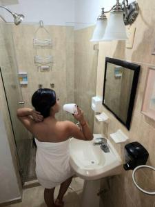 una mujer de pie en un baño que se seca el pelo en Departamento CENTRICO, Tv smart, minisplit nuevo, wifi 100 mb, cocina, lavadora, asador, parking, letra i, en Ciudad Valles 52 fotos más