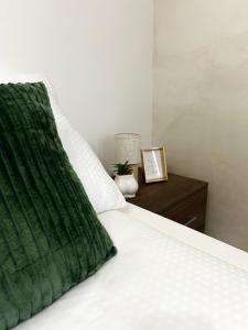 a bed with a green pillow and a night stand at Millie's apartments in Ćuprija
