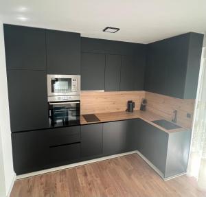 a kitchen with black cabinets and a microwave at Luxury Apartment Posusje in Posušje
