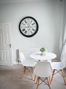 a white table and chairs with a clock on the wall at London Oval Apartment in London