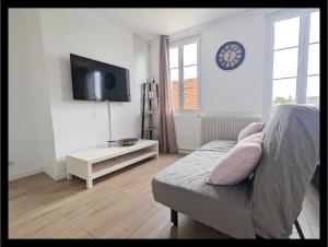 Una sala de estar con un sofá y un reloj en la pared. en maison, en Martot