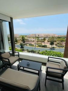 un soggiorno con sedie, tavolo e ampia finestra di Ocean and Sunset View Appartement Taghazout bay a Tamraght Ouzdar
