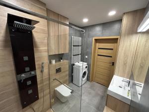 a bathroom with a toilet and a sink and a washing machine at Apartament Golden Flight in Warsaw