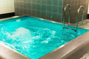 a large tub filled with blue water in a bathroom at Azhur Hotel in Tambov