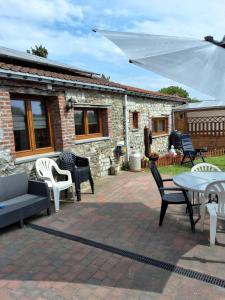 a patio with chairs and tables and a white umbrella at Le petit nid in Brugelette