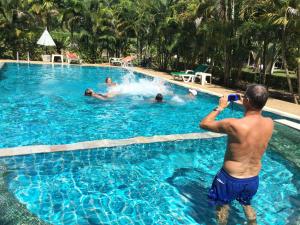 a man taking a picture of people in a swimming pool at Wild Orchid Villa Krabi in Ao Nam Mao