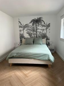 a bedroom with a bed with palm trees on the wall at Appartement en centre-ville - Local vélos disponible in Mayenne