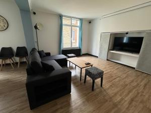 a living room with a black couch and a table at Appartement en centre-ville - Local vélos disponible in Mayenne