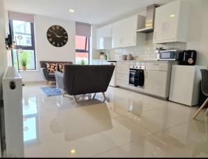 a large kitchen with a clock on the wall at En-suites Suites - Leeds City Retreat with Kitchenette- LGI Hospital- Free 5G WIFI & Netflix- University - Contractors - Short Stays in Leeds +14 photos