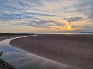 a sunset on the beach with a reflection in the water at Fylde Court in Morecambe