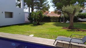 a swimming pool with a bench next to a yard at Xalet Argany in Sant Jordi d'Alfama in Les tres Cales