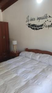 a bedroom with a white bed with a sign on the wall at Casitas sc in San Clemente del Tuyú +4 photos