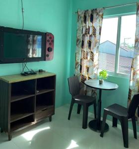 a room with a table and chairs and a tv at Bacolod City House Rental in Tangub