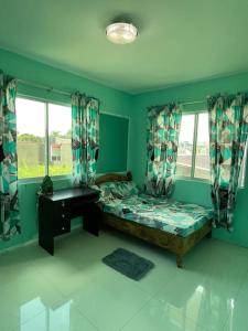 a bedroom with a bed and a desk and windows at Bacolod City House Rental in Tangub