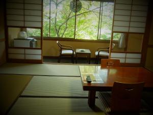 a room with a table and two chairs and a window at Yamanokami Onsen in Nagano