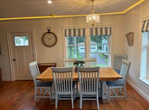 a dining room table with chairs and a clock on the wall at Gray's Manor - Lake Memphremagog in Newport