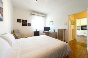 a bedroom with a large white bed and a desk at Hostly-Ai Due Passi Apartment in Pisa