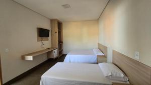 una camera d'albergo con due letti e una tv di Hotel Habitar Serra do Salitre MG a Serra do Salitre Altre 85 foto