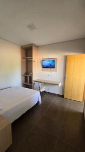 una camera d'albergo con un letto e una TV a schermo piatto di Hotel Habitar Serra do Salitre MG a Serra do Salitre