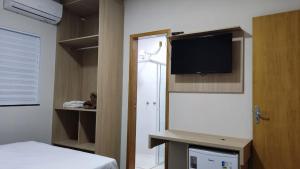 una camera con letto, TV e armadio di Hotel Habitar Serra do Salitre MG a Serra do Salitre