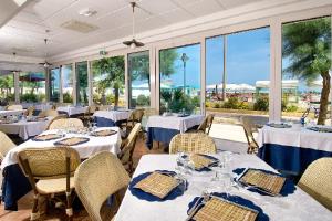 a restaurant with white tables and chairs and windows at Hotel Resort Marinella in Gabicce Mare