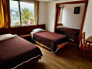 a hotel room with two beds and a mirror at Hostal Muyuyo in Puerto Ayora