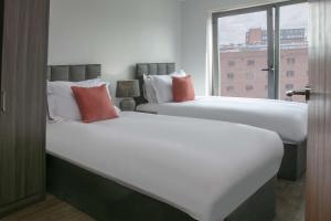 two beds in a hotel room with a window at Dockside Aparthotel, Best Western Signature Collection in Liverpool +35 photos