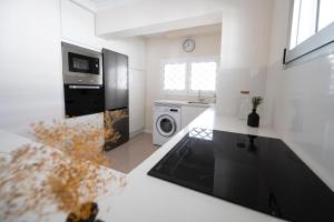 eine weiße Küche mit einem Waschbecken und einer Waschmaschine in der Unterkunft Las Nasas, Vistas al Mar, 2 dormitorios in San Agustín