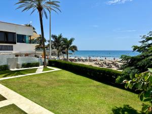 eine Wiese mit Strand und Palmen und ein Gebäude in der Unterkunft Las Nasas, Vistas al Mar, 2 dormitorios in San Agustín