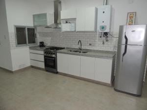a kitchen with white cabinets and a refrigerator at El Refugio de Salvador in Paraná
