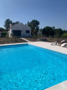 a large blue swimming pool in front of a house at Sana Home in Amieira