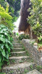 a stone stairway leading to a building with a grass roof at ECOCABAÑAS DIOSA JAGUAR tayrona in Santa Marta