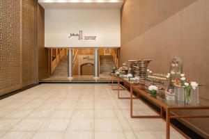 a lobby with a long row of tables with flowers at Carlton Al Moaibed Hotel in Dammam