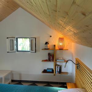 ein Schlafzimmer mit einem Bett, einem Fenster und einer Lampe in der Unterkunft As Casinhas da Madeira - Cosy Stone Cottage in a subtropical garden in Arco da Calheta