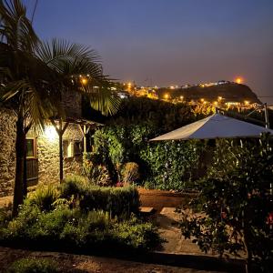 eine Terrasse mit Sonnenschirm und ein Haus bei Nacht in der Unterkunft As Casinhas da Madeira - Cosy Stone Cottage in a subtropical garden in Arco da Calheta + 15 Fotos