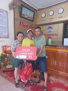 a group of three people holding a sign in a store at Khách sạn Viễn Đông in Dong Quan