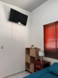 Un dormitorio con una cama y un televisor en la pared. en Tu Hogar Encantado Casa Entera con dos Habitaciones, en San Miguel