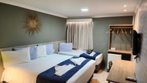 a hotel room with two beds and a television at Pousada Portomares in Porto De Galinhas