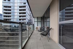a balcony with two chairs on a building at Elegant City Fringe Condo w Pool & FREE Parking in Melbourne