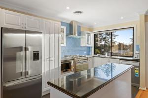 a kitchen with white cabinets and a stainless steel refrigerator at Seaside Haven on Hutton Road in The Entrance